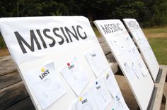 two white boards with missing notes on them sitting next to each other in front of a park bench