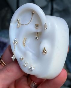 a person holding a fake ear with jewelry on it