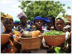 a group of women holding baskets filled with vegetables