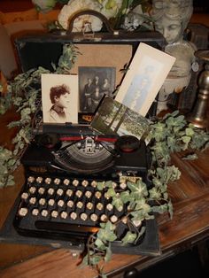 an old fashioned typewriter sitting on top of a wooden table next to some plants