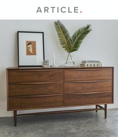 a large wooden dresser sitting next to a plant