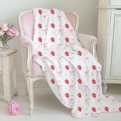 a pink chair with a blanket on it and flowers in the corner next to it