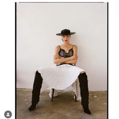 a woman sitting on top of a chair with her legs crossed and wearing black boots