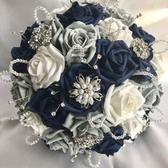 a bridal bouquet with blue and white roses on it, surrounded by crystal brooches