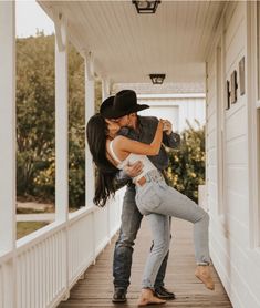 a man and woman are kissing on the porch of a house while holding each other