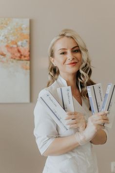 a woman in white lab coat holding up three packages of toothpaste on her hands