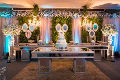 a wedding cake sits on a table surrounded by flowers and greenery at the reception