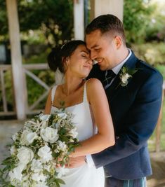 a bride and groom embracing each other in front of a gazebo