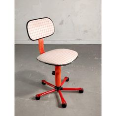 an orange and black office chair with wheels on the bottom is sitting in front of a white wall