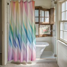 a bathroom with a shower curtain that has multicolored waves on it and a bathtub in the background