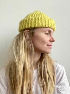 a woman with long blonde hair wearing a yellow knitted hat and looking off to the side