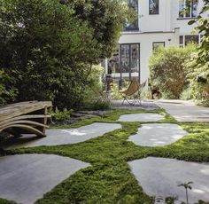 a white house with green grass on the ground and a wooden bench in front of it