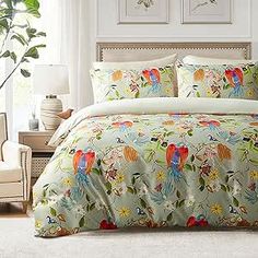 a bed covered in lots of colorful birds on it's comforter and pillows