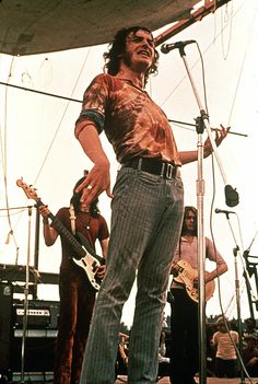 a man standing on top of a stage holding a guitar