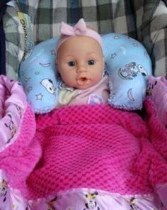 a baby in a car seat wearing a pink blanket