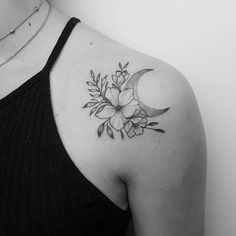 a black and white photo of a woman's shoulder with a flower tattoo on it