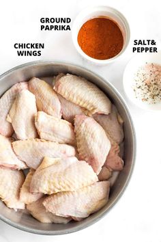 raw chicken wings in a pan with spices and seasoning next to it on a white surface