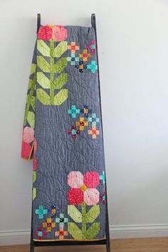 an ironing board with a quilted flower design hanging on it's side