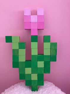 a green and pink cactus made out of blocks on top of a pile of snow