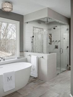 a bathroom with a large tub and walk in shower next to a window that has the letter m on it