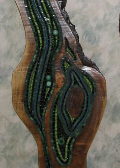 a piece of art made out of wood with beads on the bottom and green stripes