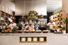 four chefs preparing food in a commercial kitchen