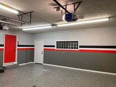 an empty room with red and grey walls, white doors and black and gray flooring