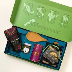 an open green box with various items in it and a wooden spoon next to it