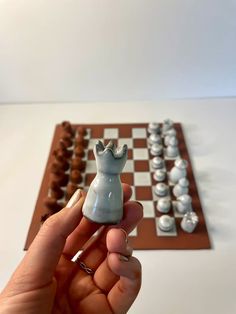 a hand is holding a miniature chess set