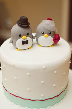 two small birds on top of a white cake