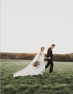 a bride and groom walking through the grass