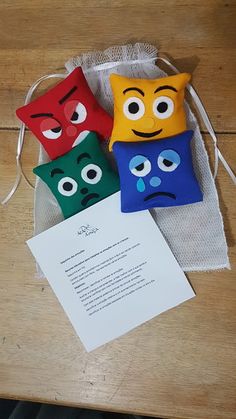 three colorful pillows with faces on them sitting next to a piece of paper and a note