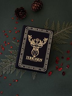 a black and gold playing card sitting on top of a table next to pine cones