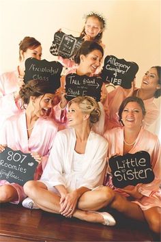 a group of bridesmaids sitting on top of a bed holding signs that read little sister