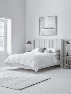 a white bedroom with a large bed and two lamps