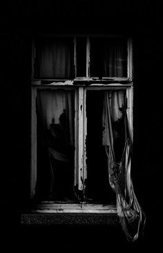 an old window with curtains in the dark