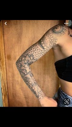 a woman with a tattoo on her arm and leg is standing in front of a wooden wall