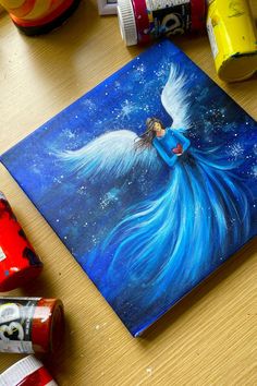 A graceful Christmas painting on canvas showing an angel with a heart in a flowing blue dress and large white wings. Angel Canvas Painting, Peaceful Decor, Easy Painting Ideas On Canvas, Painting Art Lesson, Angel Painting