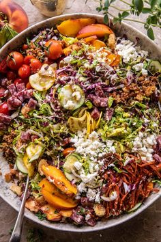 a large bowl filled with lots of different types of vegetables and fruit on top of a table