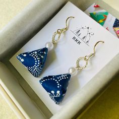 a pair of blue and white polka dot earrings in a box with a note on it