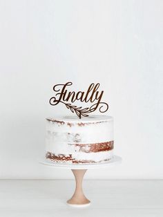 a cake with the word finally on it sitting on top of a wooden stand in front of a white wall