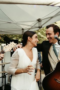 a man and woman standing next to each other near a microphone, holding guitars in their hands