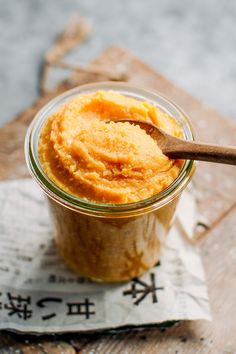 a jar filled with food sitting on top of a wooden table next to a spoon