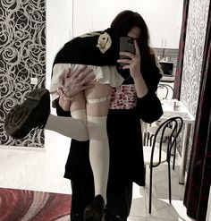 a woman is taking a selfie with her cell phone while wearing stockings and holding a purse