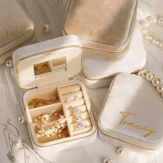 three jewelry boxes with wedding rings and bracelets in them sitting on a table next to pearls