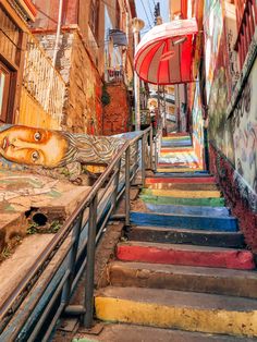 an alleyway with colorful steps and graffiti on the walls, umbrellas and stairs