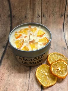 a bowl of oranges and some sliced oranges on a wooden table next to an ice cream container