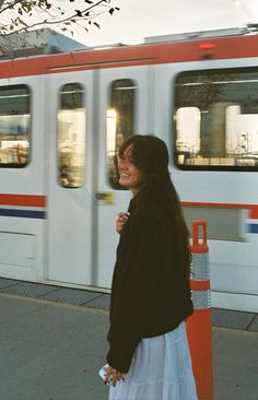 a woman is walking down the sidewalk in front of a train