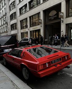 a red car is parked on the side of the street