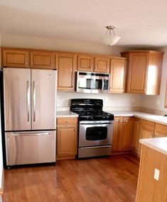 an empty kitchen with stainless steel appliances and wood flooring